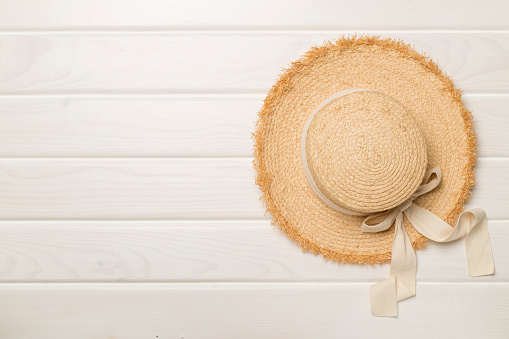 Straw hat on wooden background, top view