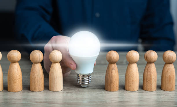 istock A man inserts a glowing light bulb idea between people. Inspire society to new ideas. Teamwork brainstorming. Research and development. Enlightenment and education. Ideology, paradigm 2018476749