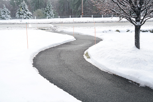 Winding pedestrian sidewalk with snow removed after winter snow