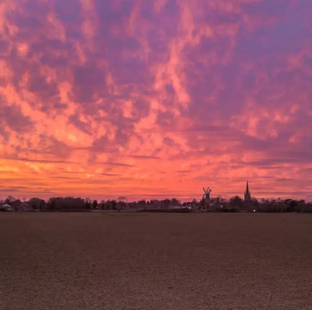 Dramatic and vibrant pink and purple sunset over the village of Moulton in Lincolnshire