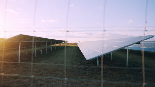 SLO MO Tracking Shot of Wire Fence at Solar Farm Under Sky in Countryside