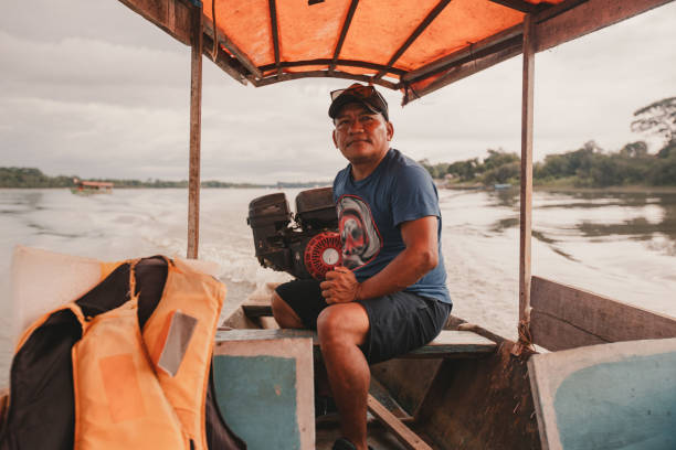 Boat captain steers motor on open air boat along estuary