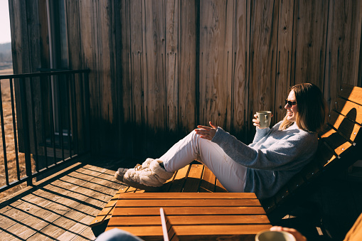 Relaxed female with coffee cup, basking in sunlight outdoors