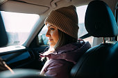 Young Woman Enjoying a Sunny Winter Day on a Car Ride Wearing a Beanie