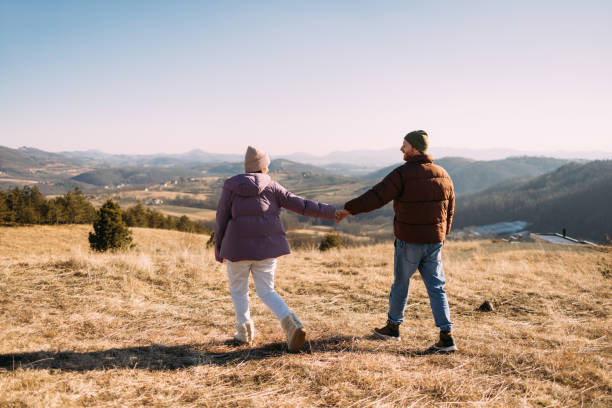 istock Happy Couple Holding Hands on a Scenic Hilltop Walk 2018595645