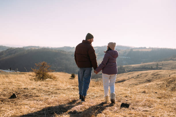istock Couple Holding Hands Walking in Countryside Landscape 2018595653
