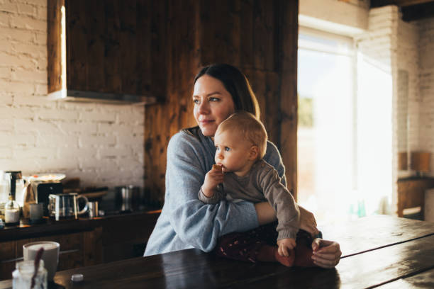 Thoughtful Mother Holding Baby in Cozy Indoor Setting