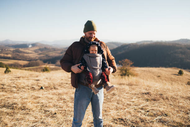 istock Father Holding Child in Carrier Enjoying a Hike in Nature 2018596182