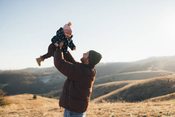 istock Joyful Father Lifting Happy Toddler in Air Outdoors in Sunset Light 2018596203