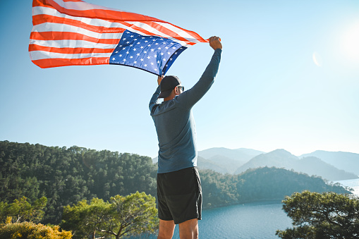 Man with american flag on the background of the sea and mountains