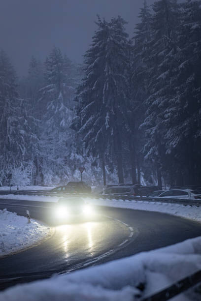 istock a car drives on a snowy road through the forest at night 2018623191