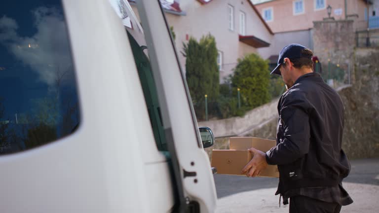 Delivery man courier delivering parcel box in town using smartphone.