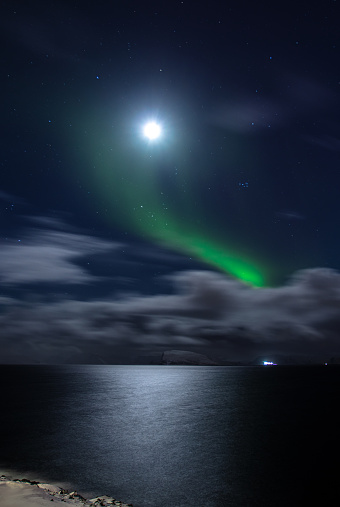 Cloudy sky, moon lights and aurora borealis on the Norwegian Sea. Hammerfest- Norway.