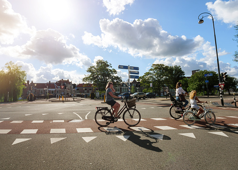 Haarlem, Netherlands - Aug 17, 2019: Side view of main street with women and young girl on bicycle crossing street on dedicated bike lane