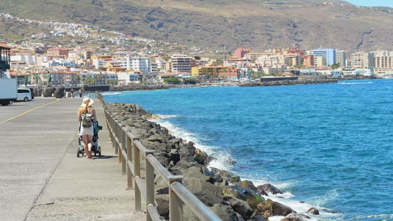 Mother with a stroller walking on a pier on vacation in Tenerife, Spain