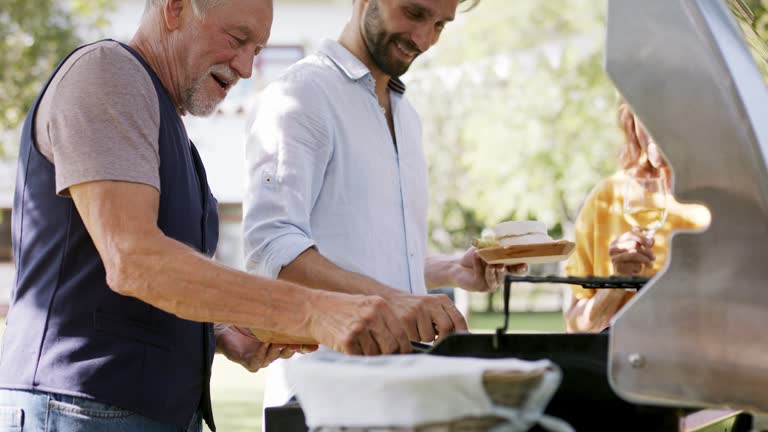 Family having a garden party, father with son barbecuing.