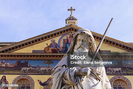Statue of Saint Paul. Fragment. Facade of Basilica of Saint Paul Outside the Walls (Basilica Papale di San Paolo fuori le Mura) at background. Rome, Italy