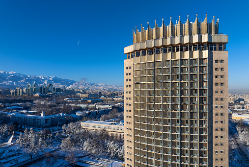 Scenic view from a quadcopter of the Kazakh city of Almaty and the Trans-Ili Alatau mountain range on a snowy winter morning