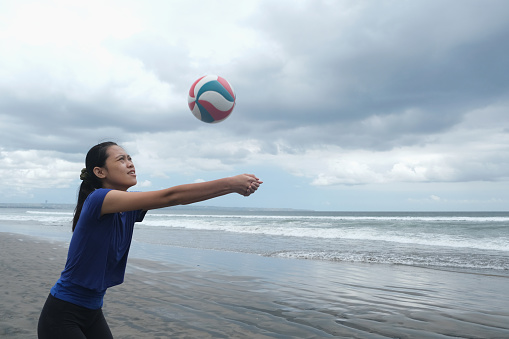 Close-up shot of young woman playing volleyball on the beach
