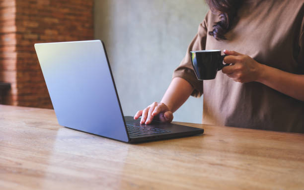 istock Closeup image of a young woman drinking coffee while working on laptop computer at home 2019266562