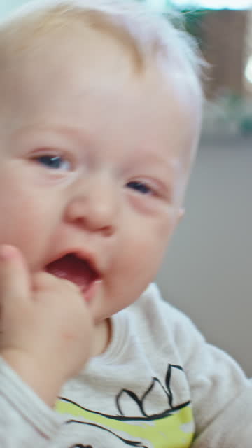 Baby Boy With Finger In Mouth Enjoying Playful Moment With Parent At Home