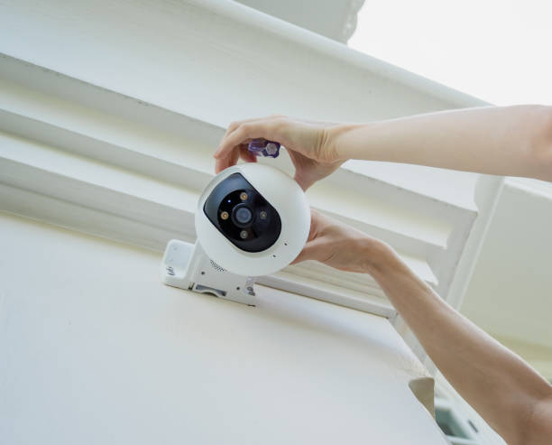 A technician installs a CCTV camera on the facade of a residential building.