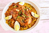 Chicken MACHBOOS mandi pulao rice biryani with fried onion, cashew nut and boiled egg served in pot dish isolated on wooden table top view arabic spicy food