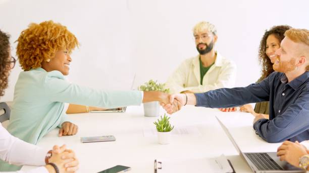 istock Business people handshaking sitting on a table with multi-ethnic coworkers 2019343294