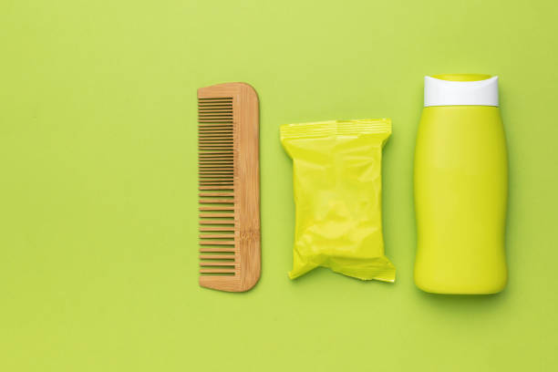 Wooden comb, shampoo and soap packaging on a green background. The concept of hair care.