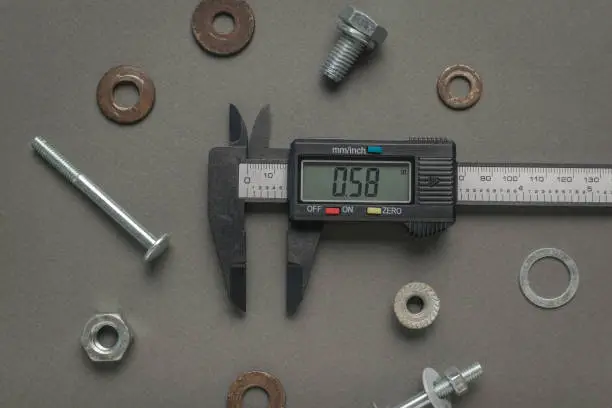 Electronic vernier caliper and metal screws and nuts. A tool for accurate measurement of dimensions.