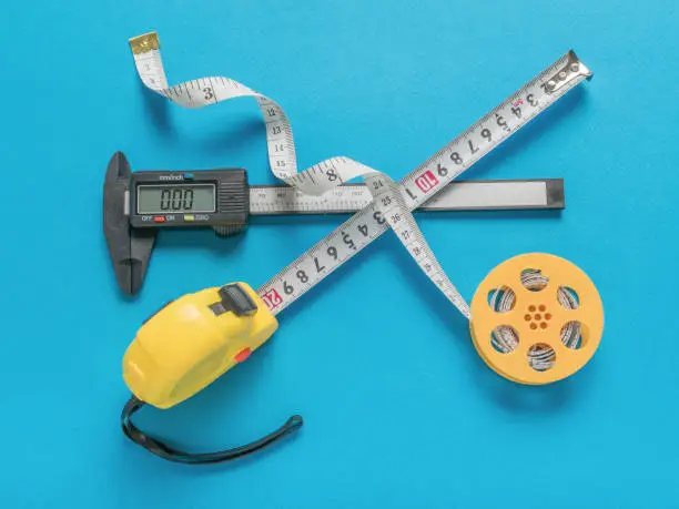 An electronic vernier caliper, a reel with measuring tape and a tape measure on a blue background. A tool for accurate measurement of dimensions.