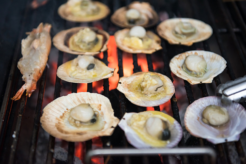 scallop and shrimp with butter on pan grilled by charcoal fire. Seafood barbecue or bbq for family party at night