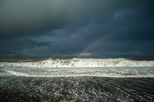 Storm in a sea or ocean with rainbow in the sky