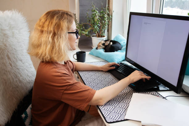 istock Remote worker, woman typing on computer, dog resting beside her, home office 2019485802