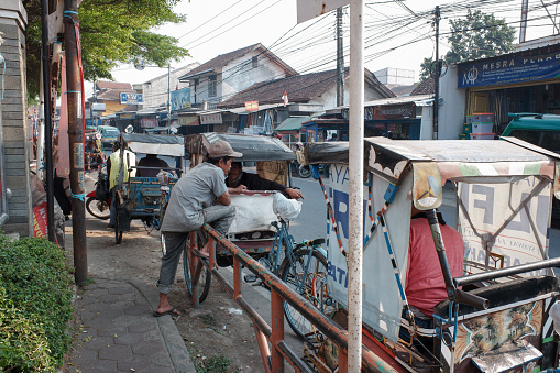 Bandung, Indonesia - October 29, 2023 : Several men driving pedicabs were waiting for passengers on the side of the road.