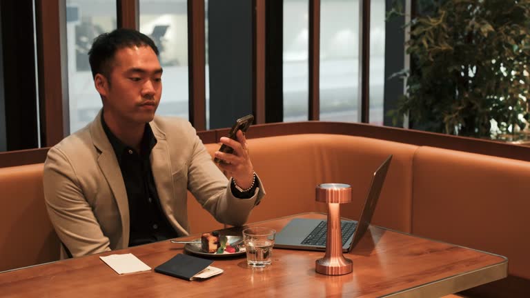 In a restaurant environment, a young Asian man is enjoying a piece of cake