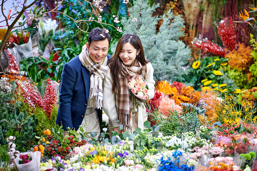 Asia couple choosing and buying flower at street market.