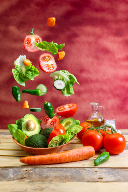 istock Bunch of vegetables falling on a plate with salad on a wooden table 2019531053