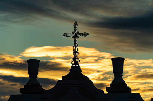 Cross against a cloudy sky, backlit