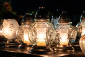 Cemetery grave candle glass lanterns, znicz light lamp illuminated at night.