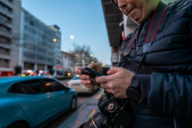 istock man traveller is looking smarthphone and camera is on neck focus on foreground street is background at niht horizontal still 2019608806