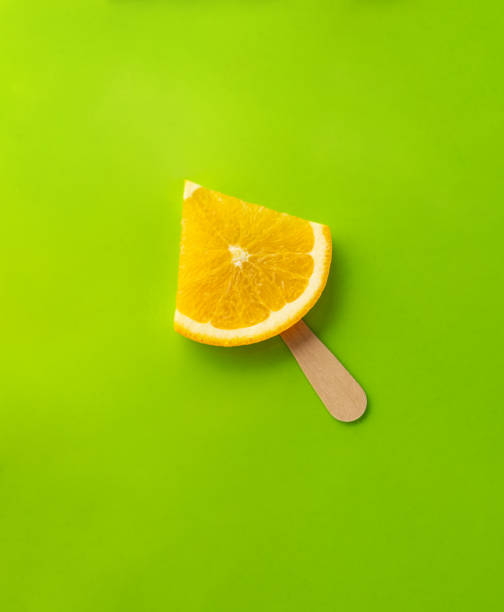 orange slice as ice cream, orange on a stick, light green background