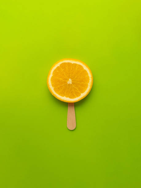 orange slice as ice cream, orange on a stick, light green background