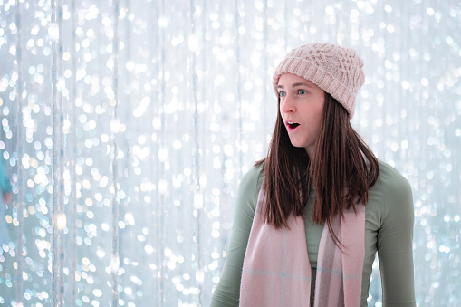 A young woman wearing a scarf and beanie shows facial expressions of being surprised