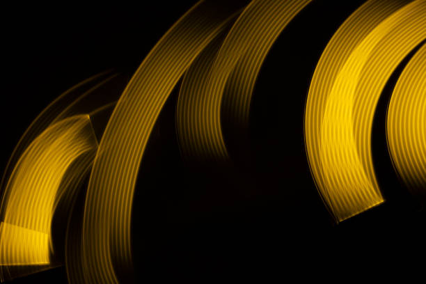 Yellow neon glowing wave of light with smooth stripes on black background, striped pattern. Abstract background with motion light effect, light painting in disco party style.