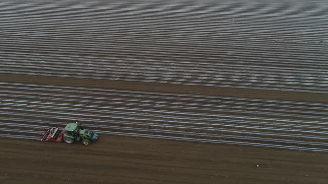 A farmer drives a planter to plant corn on a farm, aerial photo, North China