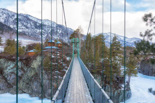Suspension bridge to John Baptist skete Barnaul Znamensky women monastery in Patmos village of Chemal in winter. Altai Republic. Russia stock photo