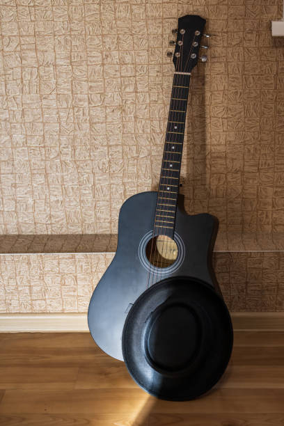 istock Acoustic guitar with i hat against the wall 2019692792