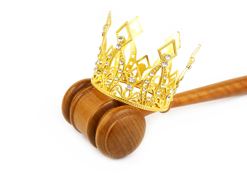 Monarchy, laws and court concept. Gold crown with judge gavel isolated on white background.