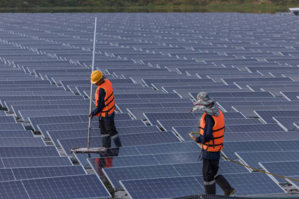istock Worker Cleaning  floating solar panels or solar cell Platform system on the lake with brush and water. Worker cleaning solar modules in a Solar Energy Power Plant 2019757576